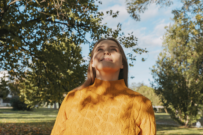 Smiling woman wearing orange sweater at autumn park