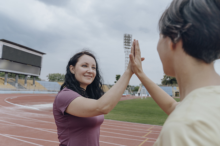 Women giving high-five on running track at stadium
