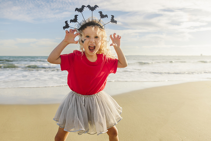 Playful girl with mouth open gesturing at beach
