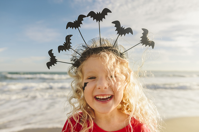 Happy girl wearing Halloween headband with bats at beach