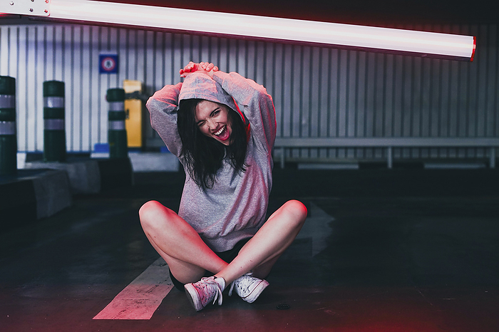 Cheerful woman sitting on ground in garage