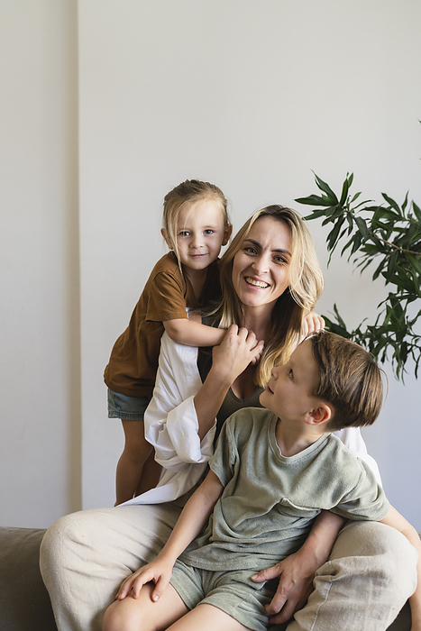 Happy blond mother with sons in living room at home