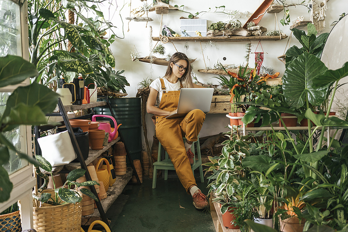 Young woman using laptop in a small gardening shop