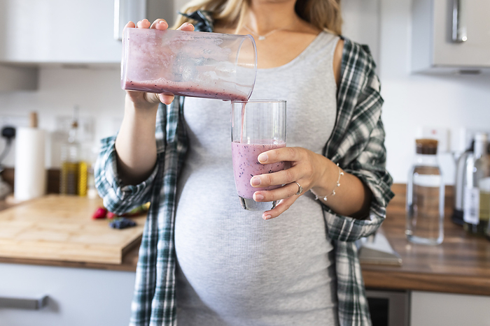 Pregnant woman pouring milkshake in glass