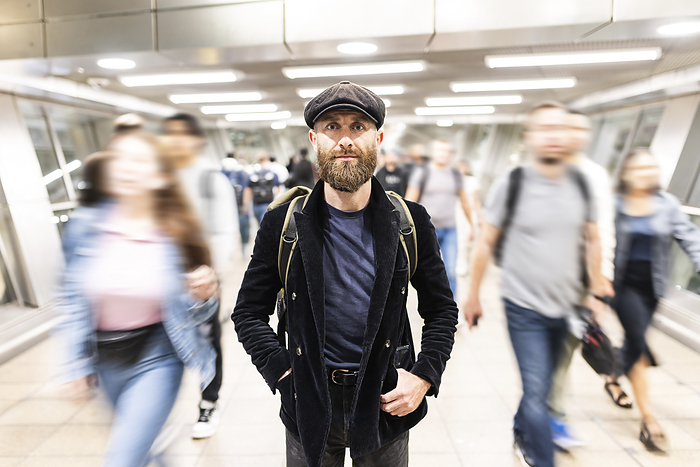 Mature man standing amidst people moving at subway station