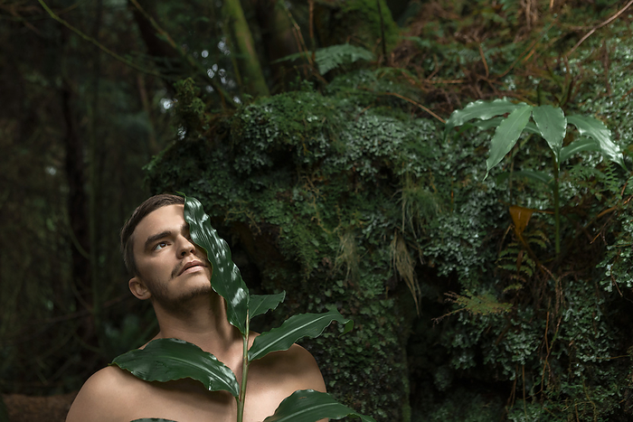 Shirtless man with leaves near plants in forest