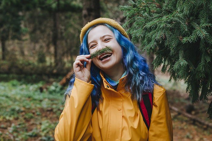 Smiling woman smelling twig in forest