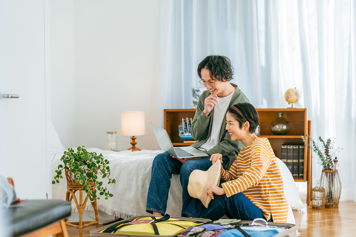 Japanese couple making a reservation on the web while preparing for a trip (man & woman / People)