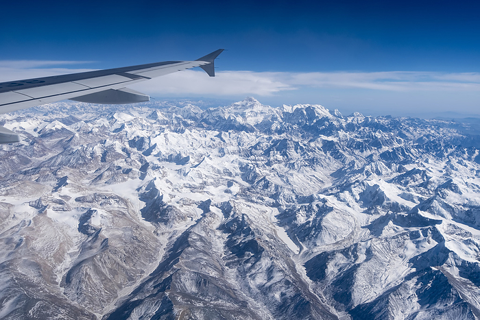 Jet in flight above the mountains of the high Tibet plateau; Lhasa, Tibet, China, by Michael Melford / Design Pics