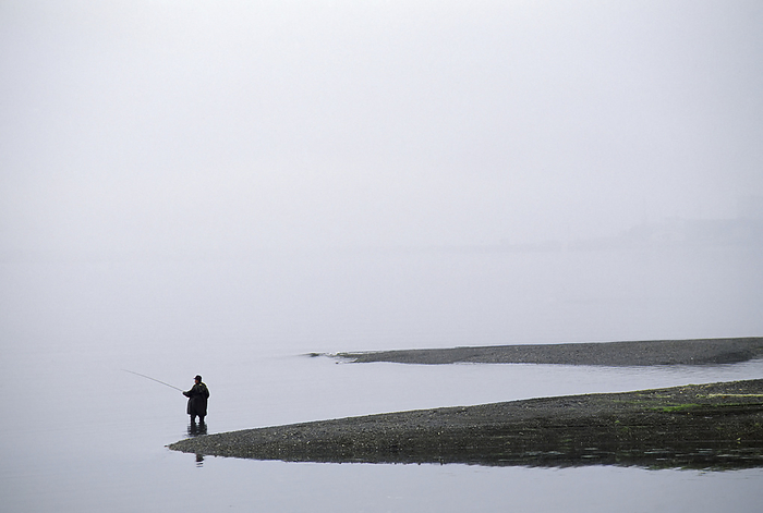 Lone fisherman fishing on a misty coast; Orleans, Cape Cod, Massachusetts, United States of America, by Michael Melford / Design Pics