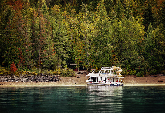 A vacation houseboat parked on the shoreline of Shuswap Lake in autumn; Shuswap Lake, British Columbia, Canada, by LJM Photo / Design Pics