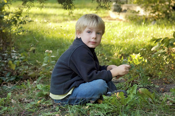 Young boy sits outdoors in a garden; Lincoln, Nebraska, United States of America, by Joel Sartore Photography / Design Pics