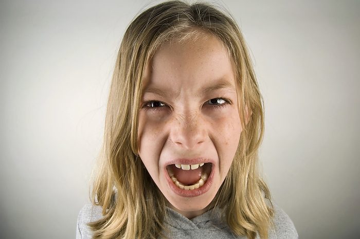 Preteen girl with an angry expression against a grey background; Studio, by Joel Sartore Photography / Design Pics