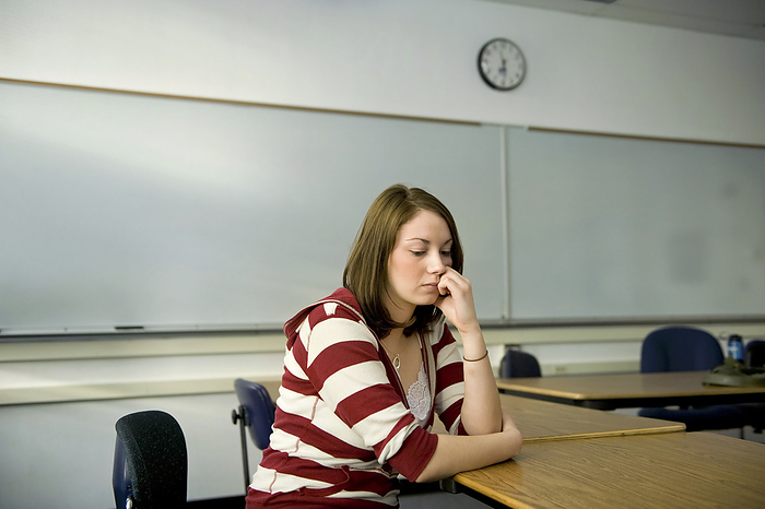 College student sits at a desk looking bored in a classroom; Fairbanks, Alaska, United States of America, by Joel Sartore Photography / Design Pics