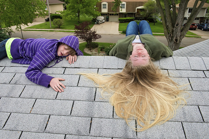 Boy and teenage girl lay on rooftop of house; Elkhorn, Nebraska, United States of America, by Joel Sartore Photography / Design Pics