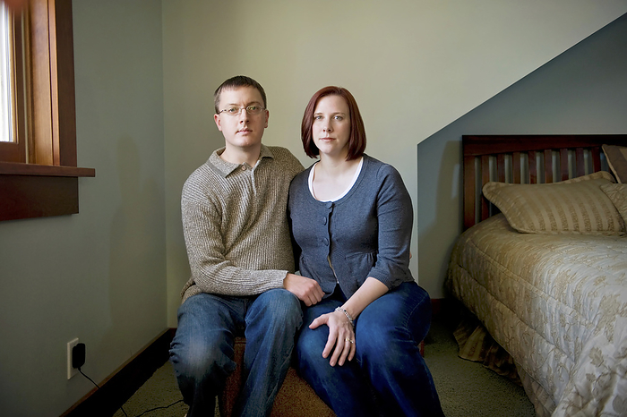Portrait of a young couple sitting in their bedroom beside their bed; Lincoln, Nebraska, United States of America, by Joel Sartore Photography / Design Pics