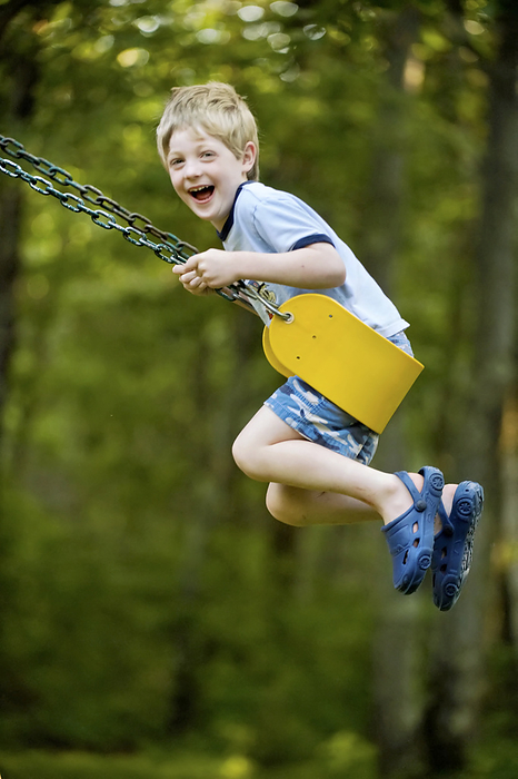 Young boy swings on a swing set; Cross Lake, Minnesota, United States of America, by Joel Sartore Photography / Design Pics