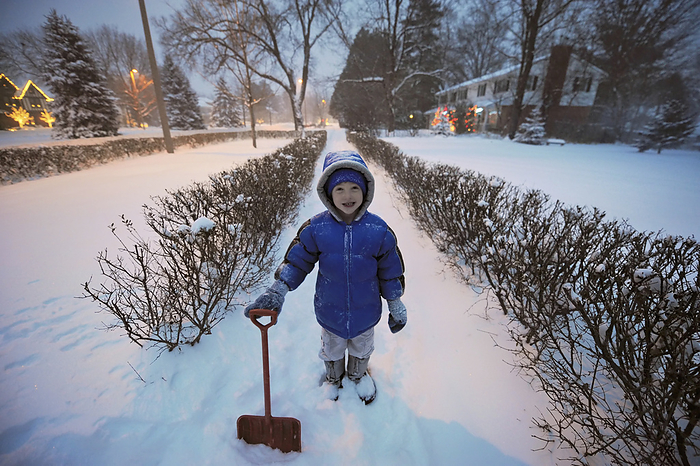 Young boy shoveling snow in front of his house; Lincoln, Nebraska, United States of America, by Joel Sartore Photography / Design Pics
