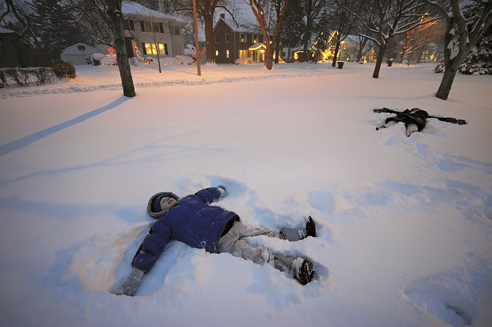 Two siblings make snow angels in their front yard; Lincoln, Nebraska, United States of America, by Joel Sartore Photography / Design Pics