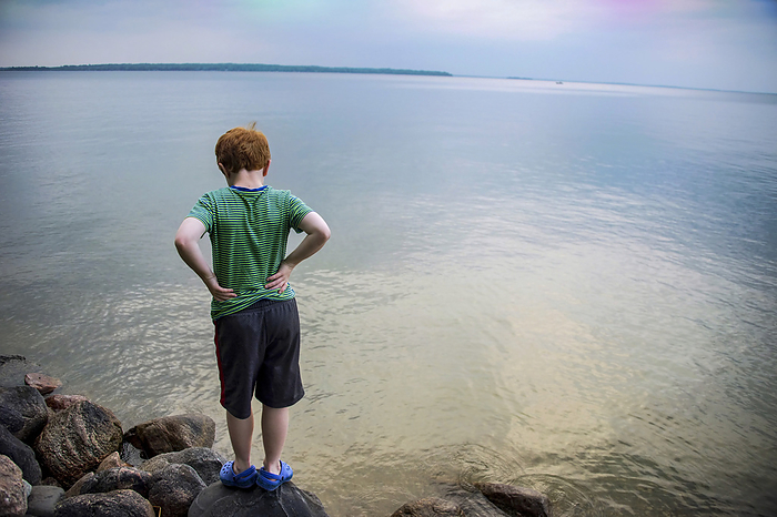 Young boy stares out over the water of Leech Lake in Minnesota, USA; Leech Lake, Minnesota, United States of America, by Joel Sartore Photography / Design Pics