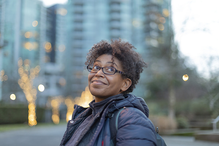 Close-up portrait of a woman standing outdoors in Vancouver at twilight, smiling and looking upward; Vancouver, British Columbia, Canada, by Lorna Rande / Design Pics