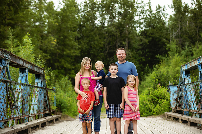 Portrait of a smiling family standing on a trestle walkway in a park in summer; Edmonton, Alberta, Canada, by LJM Photo / Design Pics