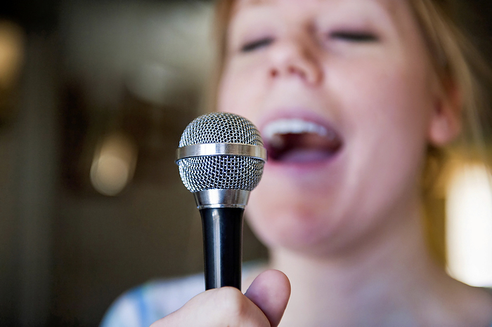 Young woman sings a song using a microphone; Lincoln, Nebraska, United States of America, by Joel Sartore Photography / Design Pics