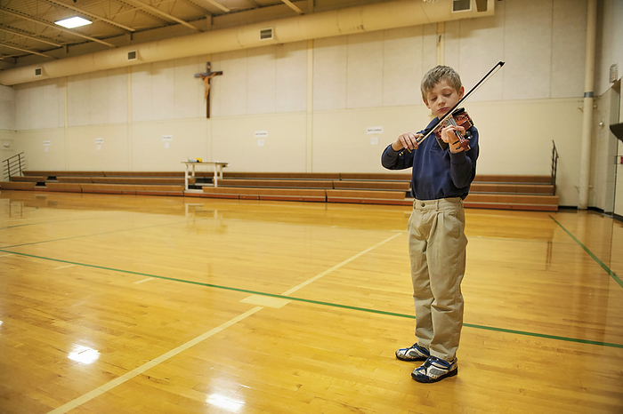 Boy practices his violin in a gymnasium before a talent show; Lincoln, Nebraska, United States of America, by Joel Sartore Photography / Design Pics