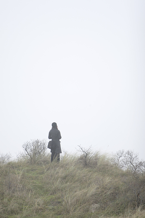 Woman Standing In Fog On Top Of Dunes Looking At The North Sea, Schiermonnikoog Island, Netherlands, by Mark Jurkovic / Design Pics