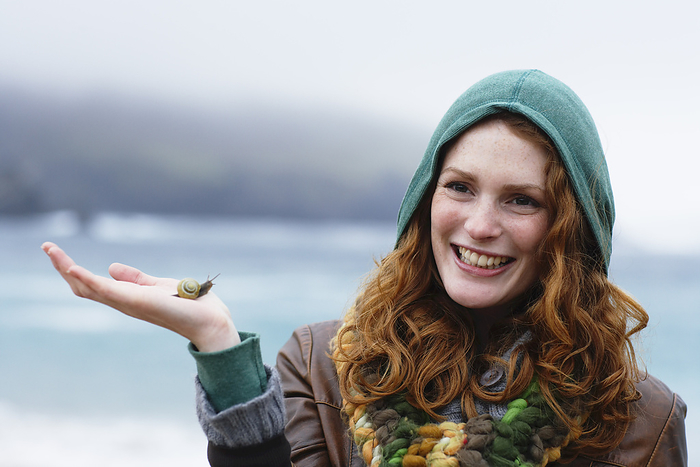Woman Holding Snail on Beach, Ireland, by Masterfile / Design Pics