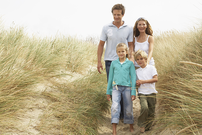 Portrait of Family Walking Through Tall Grass on Beach, by Masterfile / Design Pics