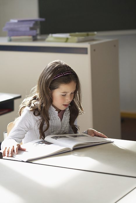 Girl Reading Book in Classroom, by Masterfile / Design Pics