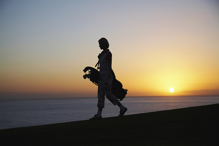 Woman with Golf Bag at Dusk, by Masterfile / Design Pics