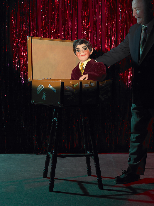 Ventriloquist with Dummy in Box on Stage, by Masterfile / Design Pics