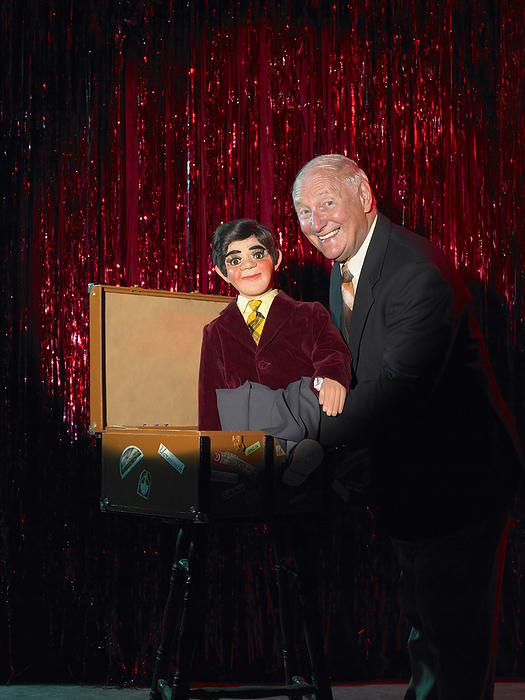 Ventriloquist with Dummy in Box on Stage, by Masterfile / Design Pics