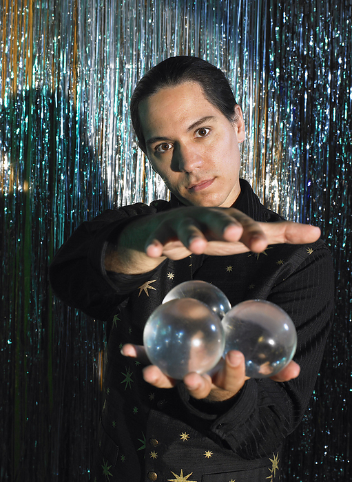 Magician on Stage with Crystal Balls, by Masterfile / Design Pics