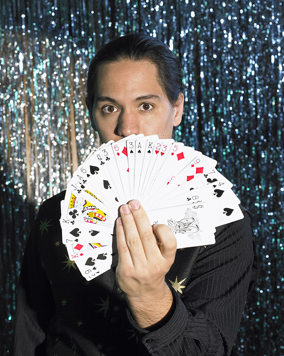 Magician on Stage Displaying Card Deck, by Masterfile / Design Pics