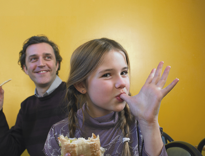 Father and Daughter Eating Fast Food, by Masterfile / Design Pics