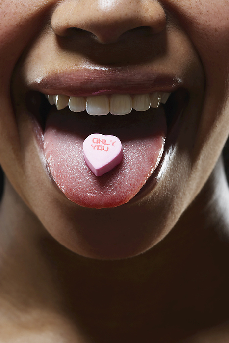 Woman with Valentine Candy on Tongue, by Masterfile / Design Pics
