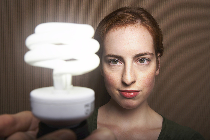 Woman Holding Energy Efficient Light Bulb, by Masterfile / Design Pics