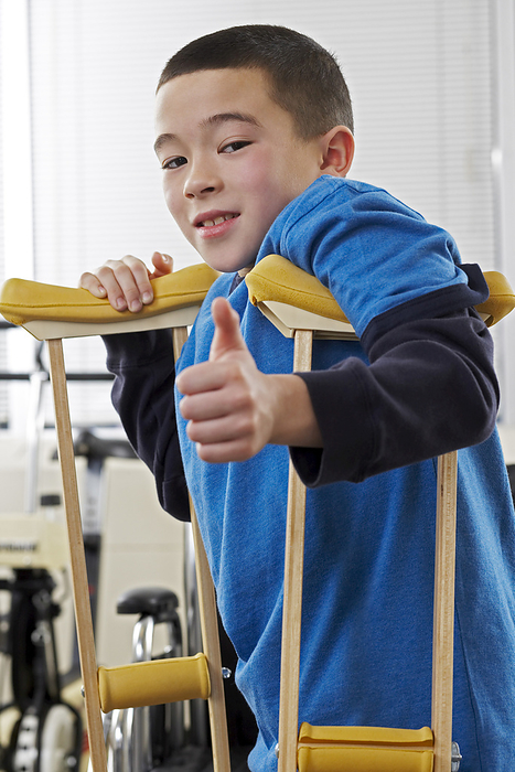 Portrait of Boy Giving the Thumbs Up Sign using Crutches, by Masterfile / Design Pics