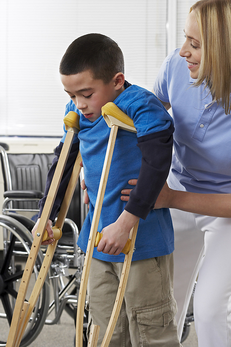 Female Physiotherapist Helping Boy on Crutches, by Masterfile / Design Pics