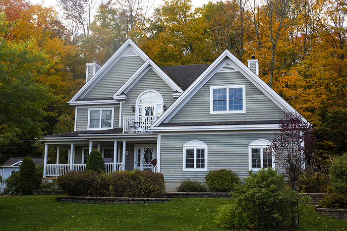 House with grey siding and autumn coloured trees; Bromont, Quebec, Canada, by David Chapman / Design Pics