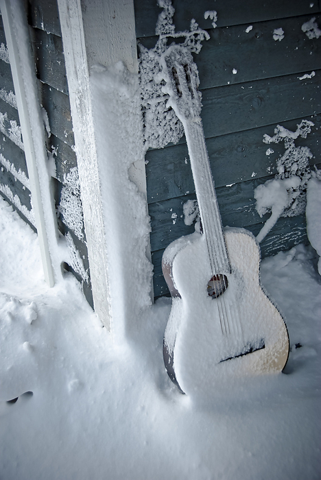 Snow-coverd guitar on a snowy porch; Fairview, North Carolina, United States of America, by Amy D. White / Design Pics