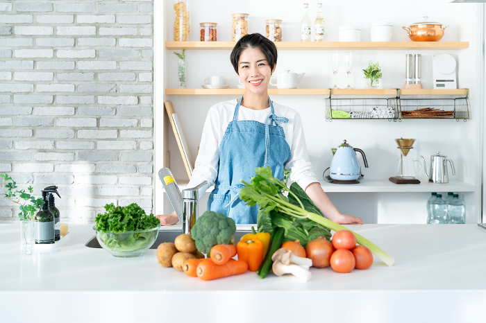Smiling young Japanese woman standing in the kitchen (People)