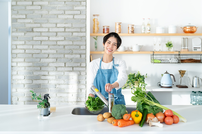 Smiling young Japanese woman standing in the kitchen (People)
