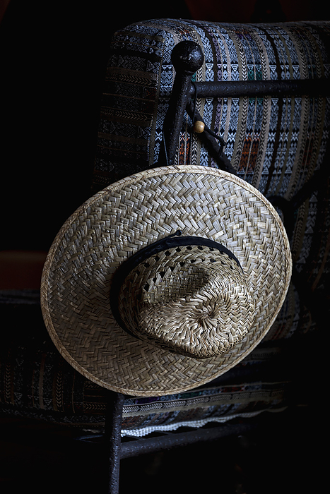Straw hat hanging on chair, by Dermot Conlan