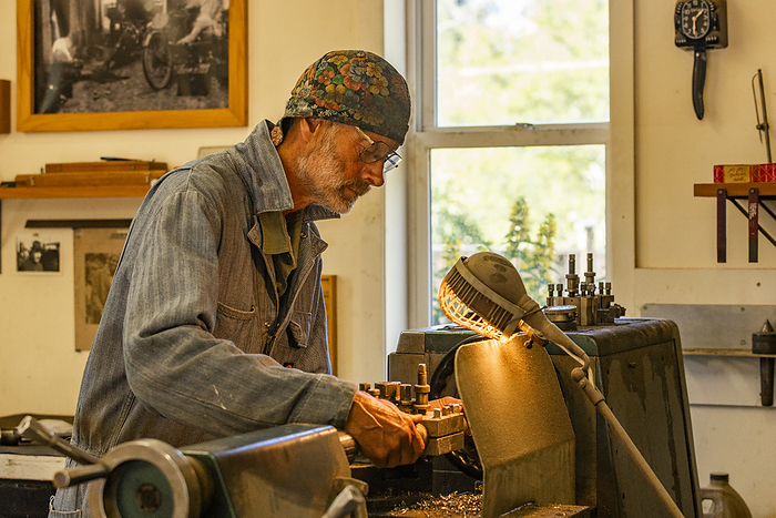 Senior artisan wood and metal craftsman works with tools in workshop, by Steve Smith