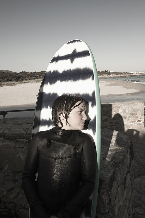 portrait of young surfer at Onrus Beach, Hermanus, South Africa Portrait of boy  10 11  posing against surfboard at Onrus Beach, by Marc Romanelli
