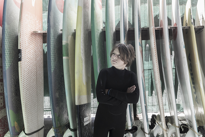 portrait of young surfer posing with surf boards Boy  10 11  posing in front of surfboards, by Marc Romanelli